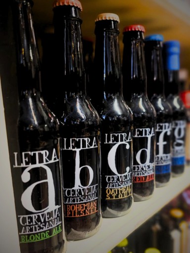 Bottles from the Letra beer range are arranged and lined up on a shelf, displaying colorful and clearly visible labels.