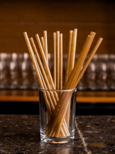 Palhinhas sustentáveis de fibra de agave num copo sobre o balcão de um bar.