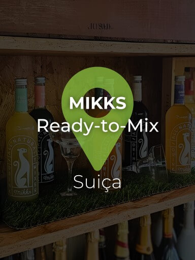 Várias garrafas Mikks Drinks com dois copos de margarita sobre uma estante de cortiça da garrafeira Black Pepper and Basil, com tapete de relva artificial por baixo_1