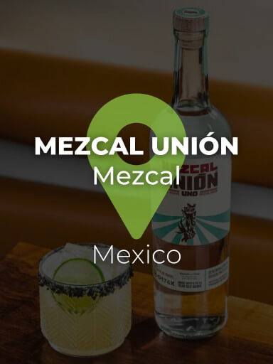Bottle of Mezcal Únion on the table with a cocktail next to it._1